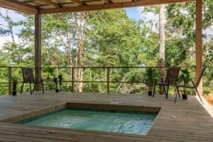 Creekside deck with pool, trees, and seating in Costa Rica real estate setting.
