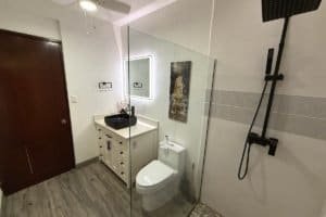 Modern bathroom with glass shower, vanity, and toilet in a tiled room.