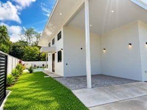 Modern white villa with covered porch, pool area and green lawn in Dominical Real Estate.