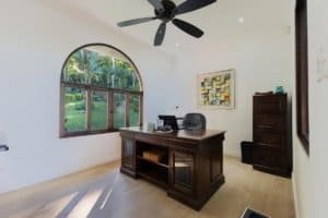 Bright home office with large arched window, wooden desk, and mountain view.