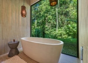Soaking tub with forest view in a modern bathroom.