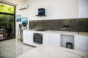 Bright kitchen with white cabinets, black marble backsplash, and stainless appliances in Costa Rica.