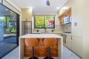 Bright modern kitchen with island and seating under natural light.