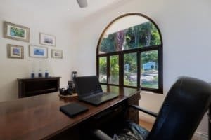 Cozy home office with large window overlooking lush greenery and mountains.