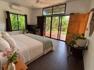 Interior of a tropical bedroom with large windows and outdoor view.