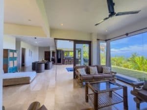 Spacious living room with ocean view, modern furniture, and pool access.