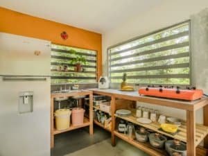 Bright kitchen with large windows, wooden shelves, and cooking essentials.