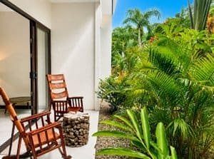 Garden view from a Costa Rican condo balcony with chairs and lush greenery.