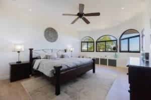 Spacious bedroom with ocean views, arched windows, and modern decor.