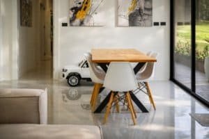 Modern dining area with wooden table and white chairs by large glass doors in Costa Rica home.