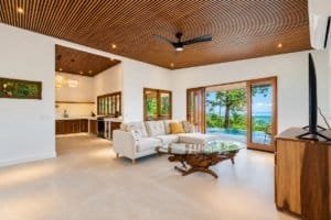 Bright living room with ocean view, modern furniture, and a wooden ceiling in Costa Rica home.