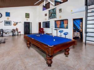Spacious living room with pool table, artwork, and staircase in Costa Rica.