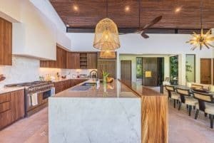 Luxury ocean view villa kitchen with island, wooden ceilings, and marble countertops.