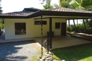 Dominical real estate single-story house with covered patio and lush tropical landscaping.