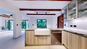 Modern tropical kitchen with wood cabinets and white countertops in a bright open-plan home.