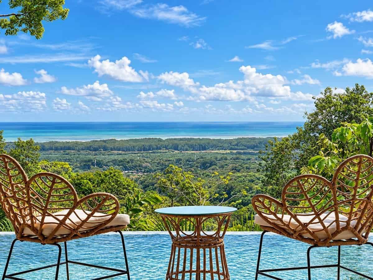 Dominical area infinity pool with wicker lounge chairs and meadow to ocean view.