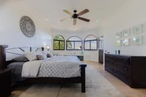 Spacious bedroom with large windows overlooking ocean and mountain views.