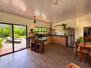 Interior of a tropical home kitchen with garden view and outdoor patio.