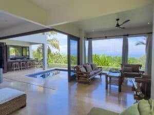Spacious living room with ocean view, pool, and tropical garden in Dominical.
