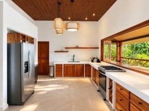 Bright kitchen with stainless steel fridge, wooden cabinets, and skylight view of greenery.