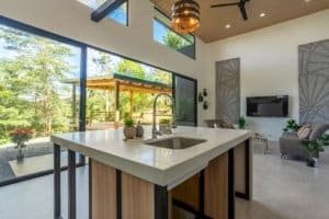 Open concept kitchen with large windows overlooking lush greenery and outdoor pavilion.