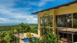Panoramic ocean view from hillside home with pool and glass windows in Costa Rica.