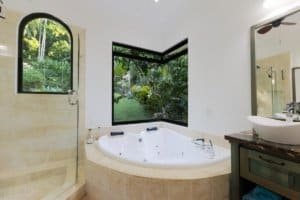 Elegant bathroom with jacuzzi and large windows overlooking lush greenery.