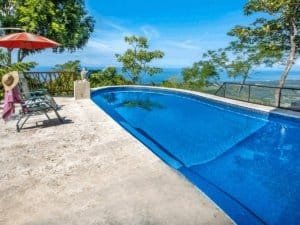 Swimming pool with ocean view, tropical trees, and lounge chairs in Dominical.