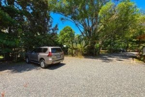 Parking lot with a car surrounded by lush tropical trees and plants in Costa Rica.