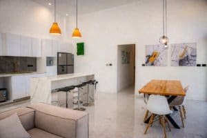 Open-plan kitchen with island, bar stools, dining table, and modern decor in a bright living space.