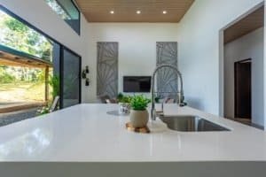 Modern kitchen island with sink and outdoor scenery in Dominical area home.