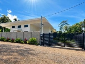 Dominical Costa Rica modern house with white façade, gated driveway, and tropical landscaping.