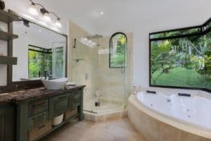 Elegant bathroom with large windows overlooking lush tropical landscape in Dominical.