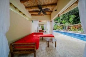 Outdoor lounge with red sofa and pool view in Dominical, Costa Rica.