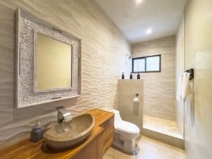 Modern bathroom with textured walls, stone sink, and ocean view window.