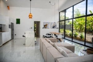 Open-plan living area with large glass walls, modern furniture, and garden view.