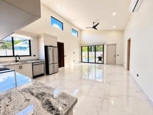 Bright open-plan kitchen and living area with marble floors and large glass doors.