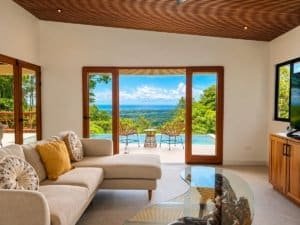 Living room with ocean view through glass doors to patio and pool.