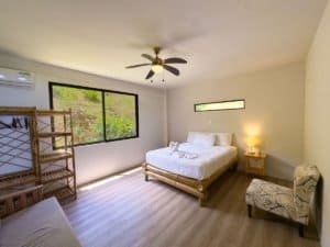 Spacious bedroom with large windows, wooden furniture, and minimalist decor.