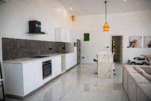 Modern kitchen and open-plan living area with marble floors in Dominical home.