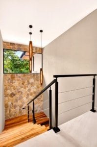 Interior staircase with stone wall, wooden steps, and modern railing.