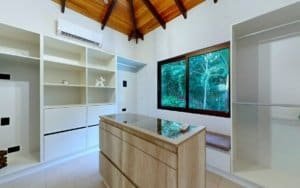 Bright kitchen with a central island and built-in shelves, large window overlooking greenery.