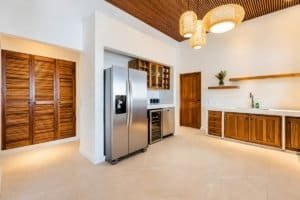 Bright kitchen with stainless steel fridge, wooden cabinets, and modern pendant lighting.