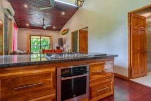 Turn-key coastal home kitchen with granite island and wooden cabinetry.
