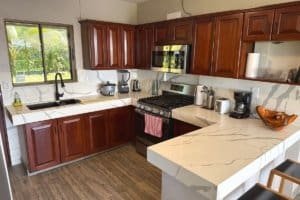 Well-equipped kitchen with dark wood cabinets, stainless steel appliances, and marble countertops.