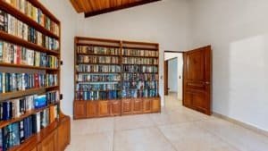Spacious home library with built-in shelves of books and a wooden door.