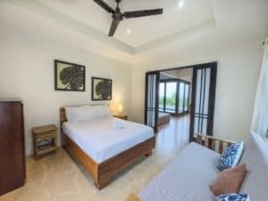 Spacious bedroom with ocean view, pool access, and tropical decor in Dominical.