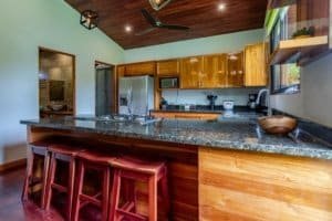 Modern coastal kitchen with granite counter, wooden cabinets, and bar seating.