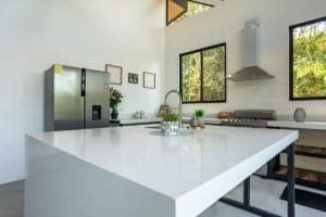 Modern kitchen with large white island, stainless appliances and bright windows.