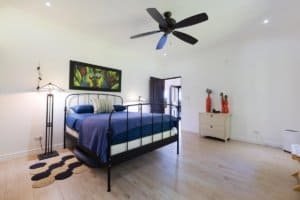 Spacious bedroom with modern decor, ceiling fan, and artwork in Costa Rica home.